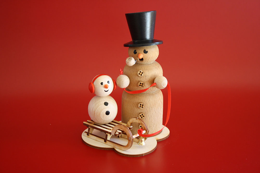 Räuchernder Schneemann mit Schlittenkind
